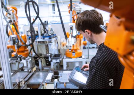 Engineer setting up automatic robot arms in smart factory, automotive industry, industrial concept Stock Photo