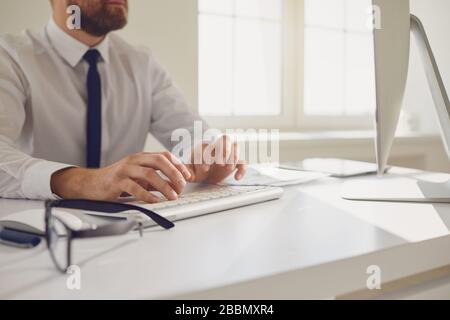 Work training online. Male hands of businessman tipping using keyboard on computer desk. Stock Photo