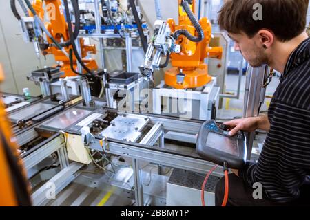 Engineer setting up automatic robot arms in smart factory, automotive industry, industrial concept Stock Photo