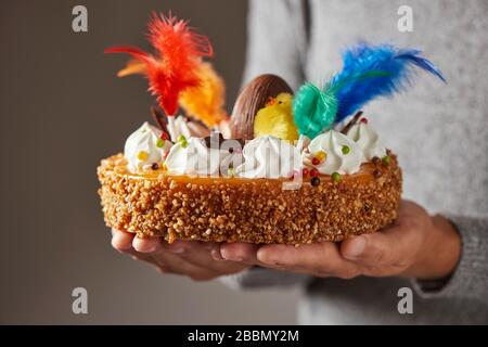 closeup of a caucasian man with a typical mona de pascua, a cake eaten in Spain on Easter Monday, decorated with a chocolate egg, a plush chick and fe Stock Photo