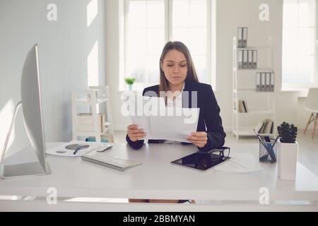 Happy businesswoman with documents in hands sitting at table Stock Photo