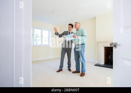 Realtor With Digital Tablet Showing Senior Man Looking To Downsize Around Retirement Home Stock Photo