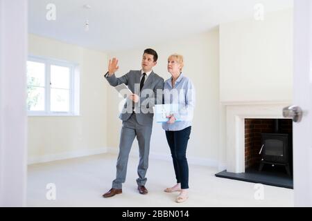 Realtor With Digital Tablet Showing Senior Woman Looking To Downsize Around Retirement Home Stock Photo