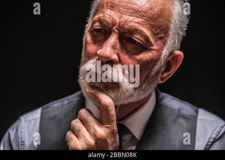 Portrait of pensive senior man on black background. Stock Photo