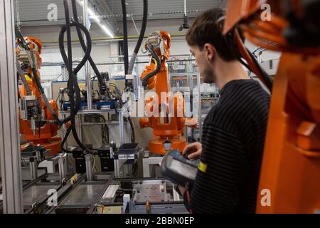 Young man programming industrial automatic robot in automotive industry Stock Photo