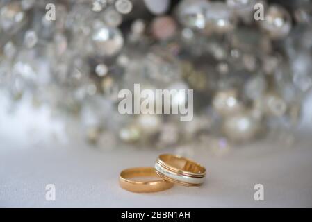 Two gold and platinum wedding rings with a silver sparkly background. Towcester, England Stock Photo
