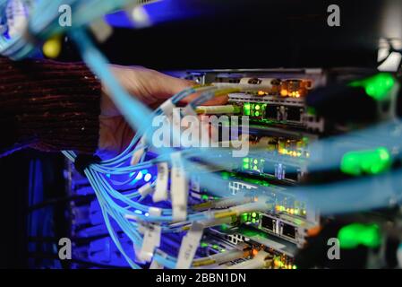 Man data center technician performing server maintenance. Replacing cables, Stock Photo