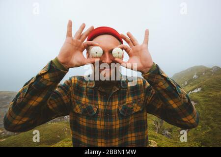 Bearded man hipster having fun outdoor  travel lifestyle summer vacations joyful positive emotions guy holding sea urchins shells like big eyeballs Stock Photo