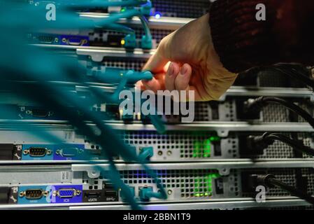 Man data center technician performing server maintenance. Replacing cables, Stock Photo