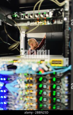 Man data center technician performing server maintenance. Replacing cables, Stock Photo