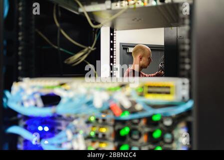 Man data center technician performing server maintenance. Replacing cables, Stock Photo