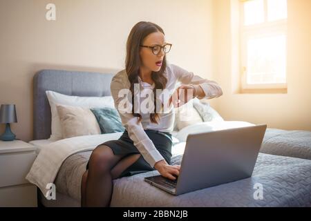 Businesswoman on business trip sitting in hotel room and working on laptop. Stock Photo