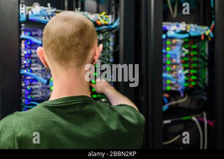 Man data center technician performing server maintenance. Replacing cables, Stock Photo