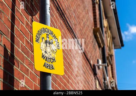 A Neighbourhood Watch area sign on a lamppost in a British street with a terraced brick house in the background Stock Photo