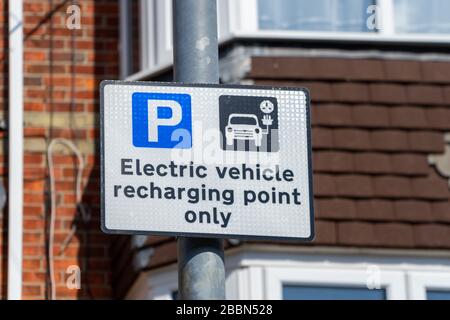 A sign on a lamppost stating that a parking bay on the street is for Electric vehicle recharging only or electric vehicle charging point