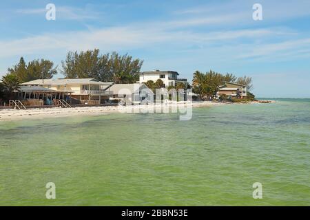 Skyline of houses along the beach at Bean Point on the north end of Anna Maria Island, Florida, with unrecognizable people walking on the sand Stock Photo