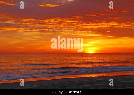 Dramatic clouds mask the sun as it rises over the Atlantic ocean to illuminate the sandy beach at Nags Head on the Outer Banks of North Carolina Stock Photo