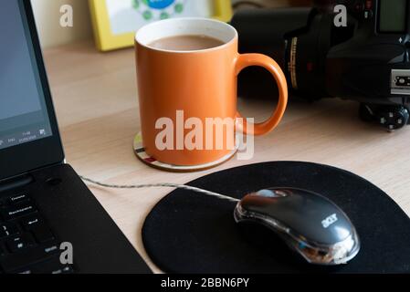 A mug of tea on a desk set up for working from home Stock Photo
