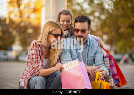 Beautiful parents and their daughter with shopping bags.Smiling happy family with many shopping bags. Stock Photo
