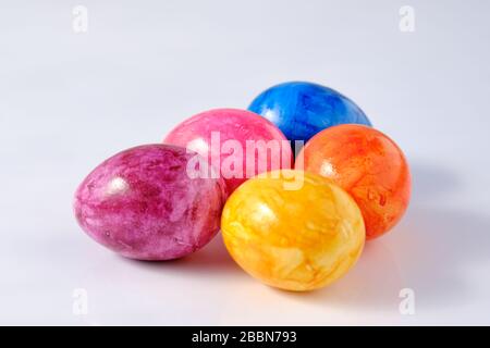 Five naturally looking coloured Easter eggs lying isolated on white background with copy space. Stock Photo