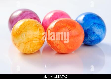 Five naturally looking coloured Easter eggs lying isolated on white background with copy space. Stock Photo