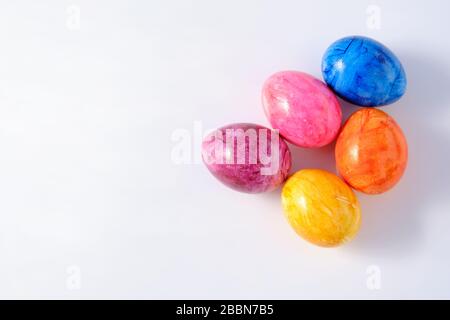 Five naturally looking coloured Easter eggs lying isolated on white background with copy space. Stock Photo