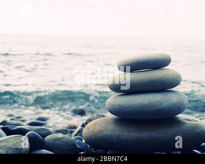 Balance, peace of mind, different sizes stones form a pyramid, Stones pyramid on pebble beach symbolizing stability, zen, harmony, balance. Shallow de