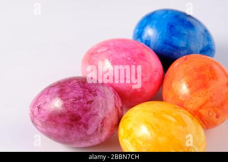 Five naturally looking coloured Easter eggs lying isolated on white background with copy space. Stock Photo