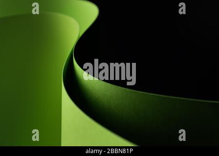 Abstract - closeup of two sheets of rolled green paper on a black background. Simple, isolated object with text space. Stock Photo