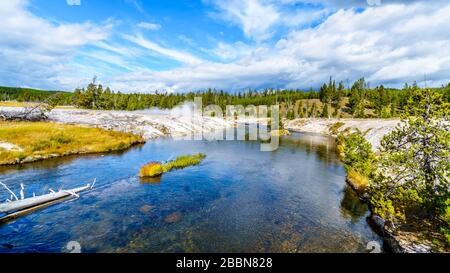 Hot water from the Oblong Geyser flowing into the Firehole River in the Upper Geyser Basin along the Continental Divide Trail in Yellowstone Stock Photo