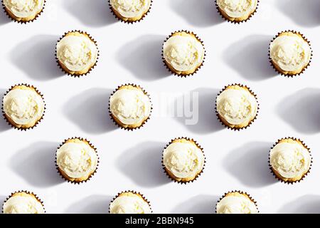 Seamless pattern made of coconut cupcake with white whipped vanilla icing cream on white background.The concept of a holiday,party,unhealthy food Stock Photo