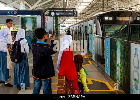 An Indonesian Family Wait On The Station Platform As A Train Approaches, The Metro (MRT), Jakarta, Indonesia. Stock Photo