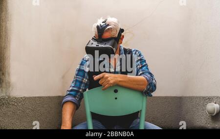 mature man is looking through the viewer of virtual reality during tough quarantine at the time of coronavirus Stock Photo