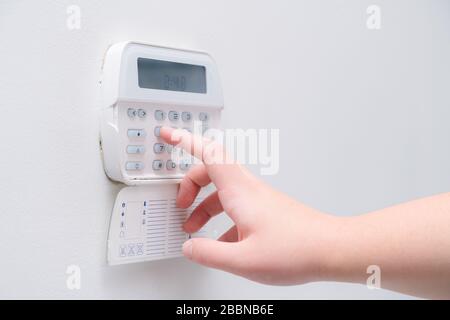 Woman hand entering alarm system password of an apartment, house of business office. Surveillance and protection console against rubbery and thief Stock Photo
