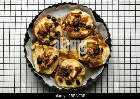 Concept of healthy food. Baked apples stuffed with dried fruit, nuts, cinnamon and sultanas in a baking tray. Top view. Stock Photo