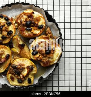 Concept of healthy food. Baked apples stuffed with dried fruit, nuts, cinnamon and sultanas in a baking tray. Top view. Stock Photo
