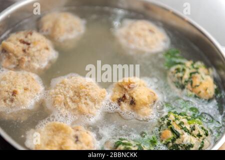 Close up of three different kinds of bread dumplings with cheese, bacon and spinach floating in pot with hot water Stock Photo