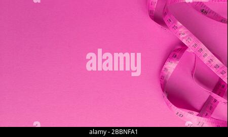 Pink centimeter on pink background. Simple flat lay with pastel texture. Fitness concept. Stock photography. Stock Photo