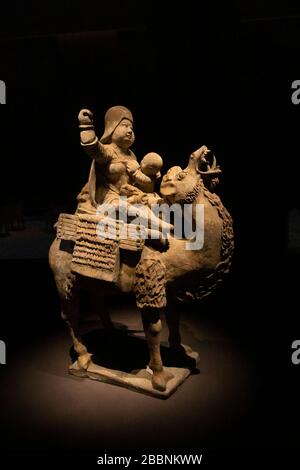 painted pottery figure of mother breastfeeding child while riding a camel, Tang dynasty (618-907), Aurora Art Museum, Shanghai, China Stock Photo
