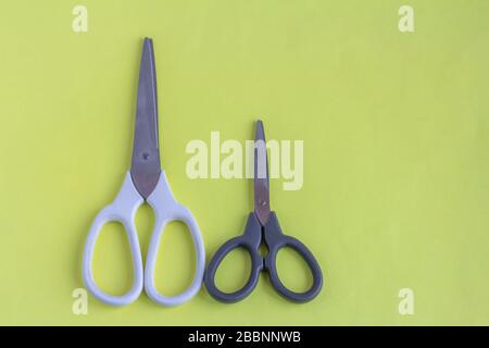 Scissors on a yellow background.White large and black small scissors for work and creativity. Stock Photo