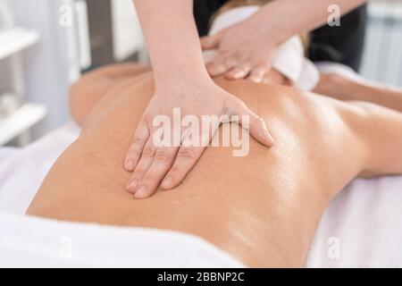 Close-up of unrecognizable masseur doing massage therapy for back to relax woman in SPA salon Stock Photo
