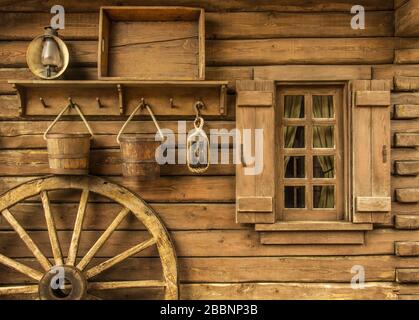 Detail of old wagon wheel next to a wooden wild west typical house Stock Photo