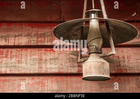 Old rusty kerosene lantern hanged on a rustic wooden wall Stock Photo