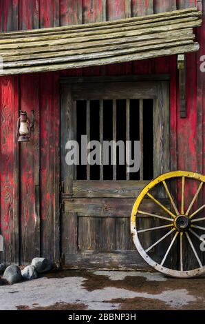 Detail of old wagon wheel next to a wooden wild west typical house Stock Photo