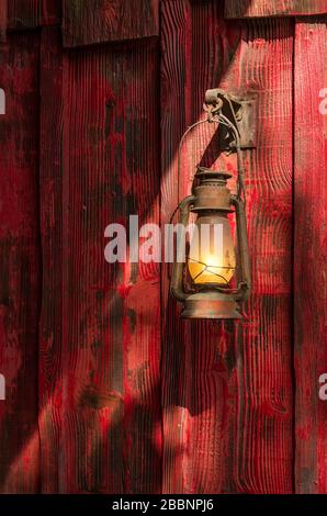 Old rusty kerosene lantern hanged on a rustic wooden wall Stock Photo