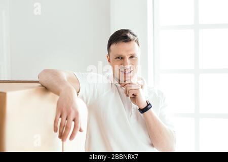 pensive young man standing near cardboard boxes Stock Photo