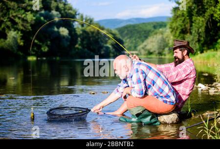 fly fish hobby of men. retirement fishery. Two male friends fishing together. big game fishing. relax on nature. happy fishermen friendship. retired father and mature bearded son. What a fish. Stock Photo