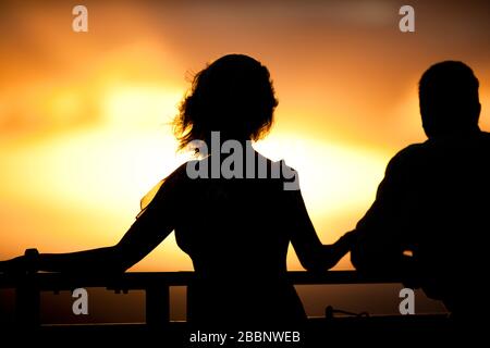Couple looking at view on cruise ship at sunset. Stock Photo