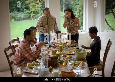 Smiling family gathered around a dining table. Stock Photo
