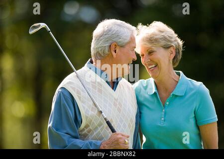 Mature couple laughing while playing golf. Stock Photo